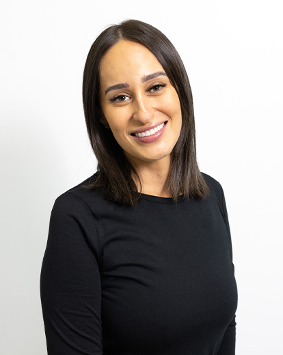 Professional headshot of woman smiling against white background, wearing black top.