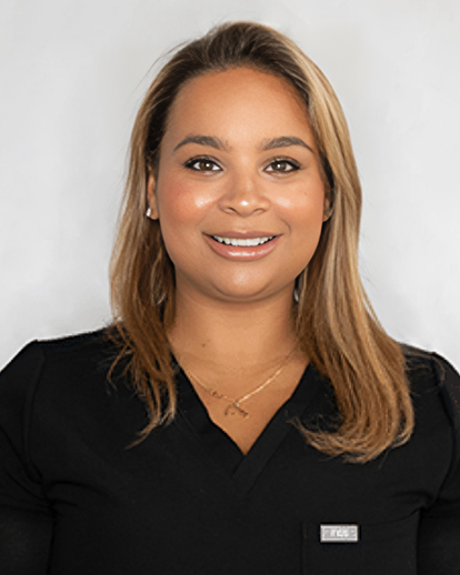 Professional headshot of a smiling woman in black scrubs against a white background.