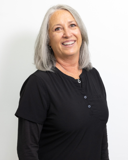 Professional headshot of a woman with long gray hair wearing black against a white background.