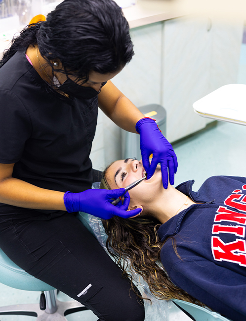 Orthodontist in blue gloves examines patient's teeth during dental appointment in clinical setting.