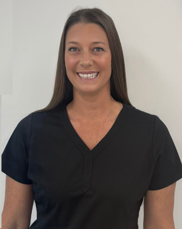 Professional headshot of smiling woman in black scrubs against white background for orthodontics practice.